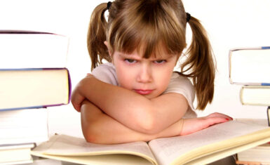 Niña con cara enojada sobre un libro. Imágen de apoyo para la temática de los berriches en los niños del Blog de Los Pinos